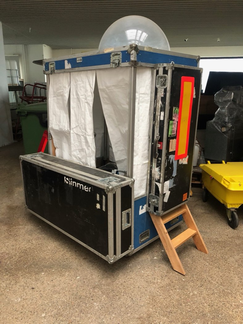 A flightcase opened into a small curtained booth with a dome window, on its own steps