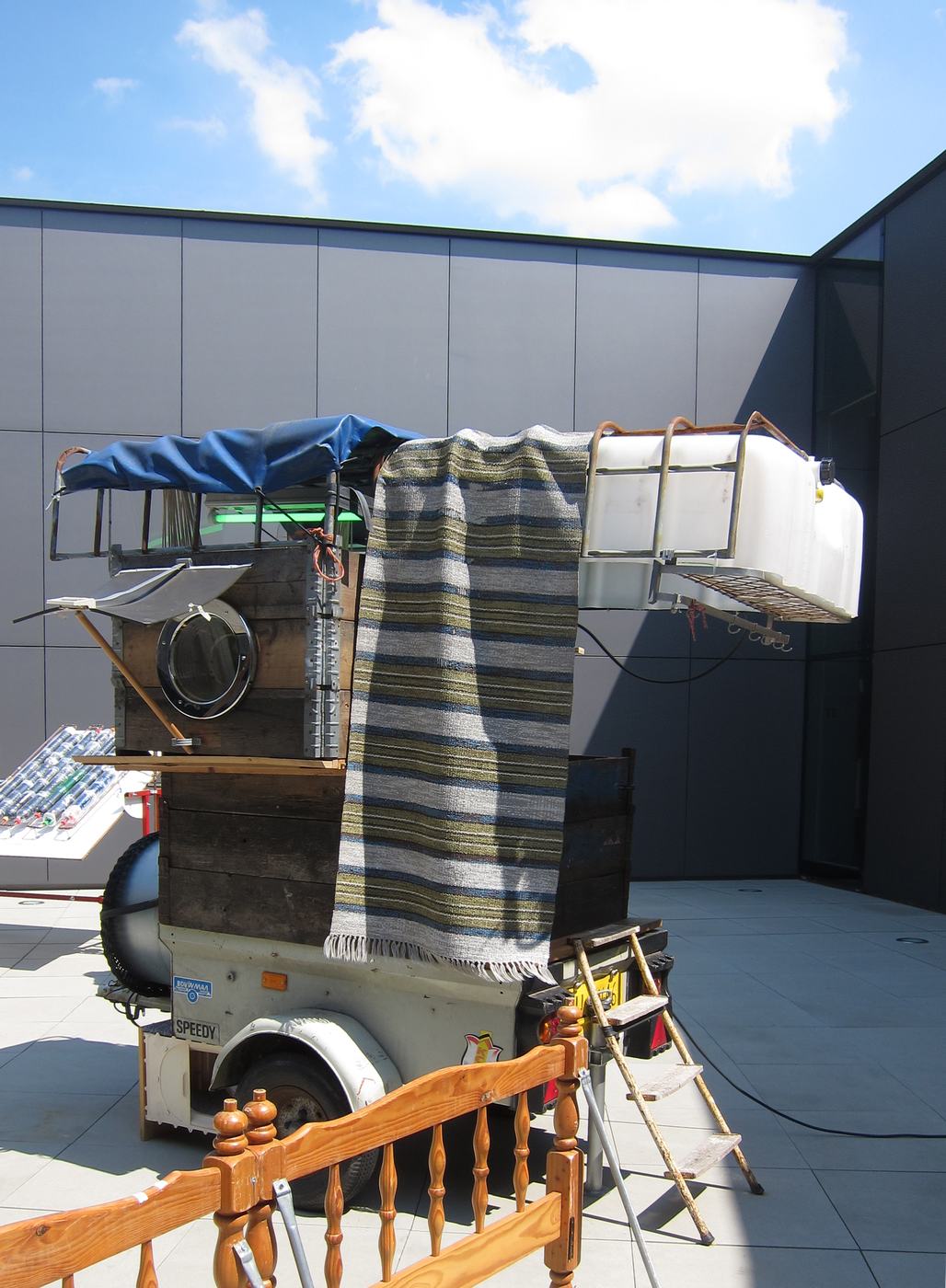 A wheeled house with a striped awning outside a museum