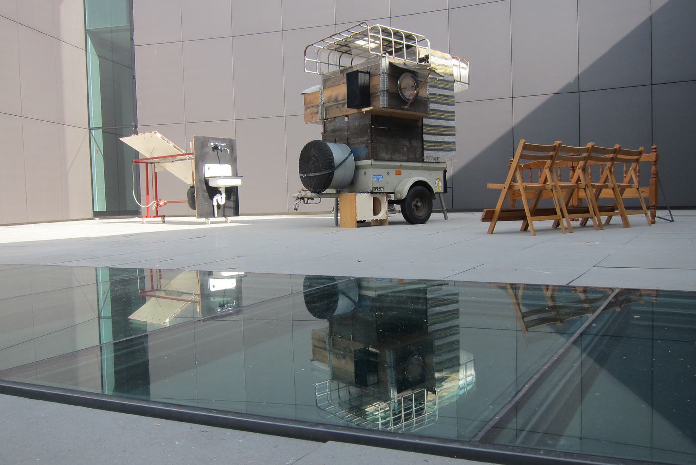 The cart on the museum forecourt, reflected in water