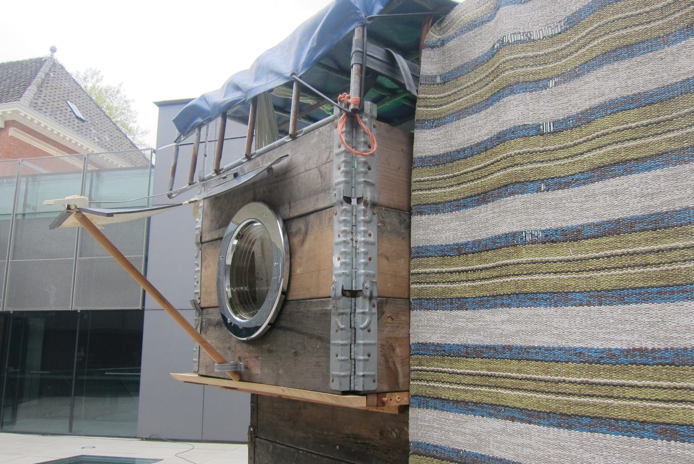 A washing machine drum set into a wall of striped fabric