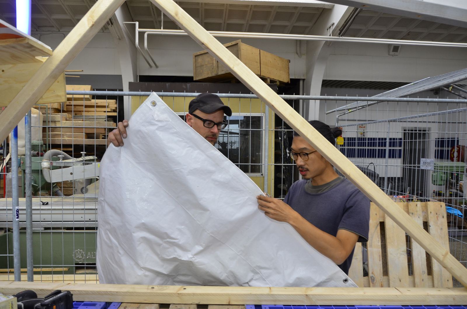 Two people stretching a sheet over the frame